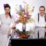 Franziska in weißem Anzug und Markus stehen am schwarzen Flügel, zwischen beiden ein prächtig bunter Blumenstrauß