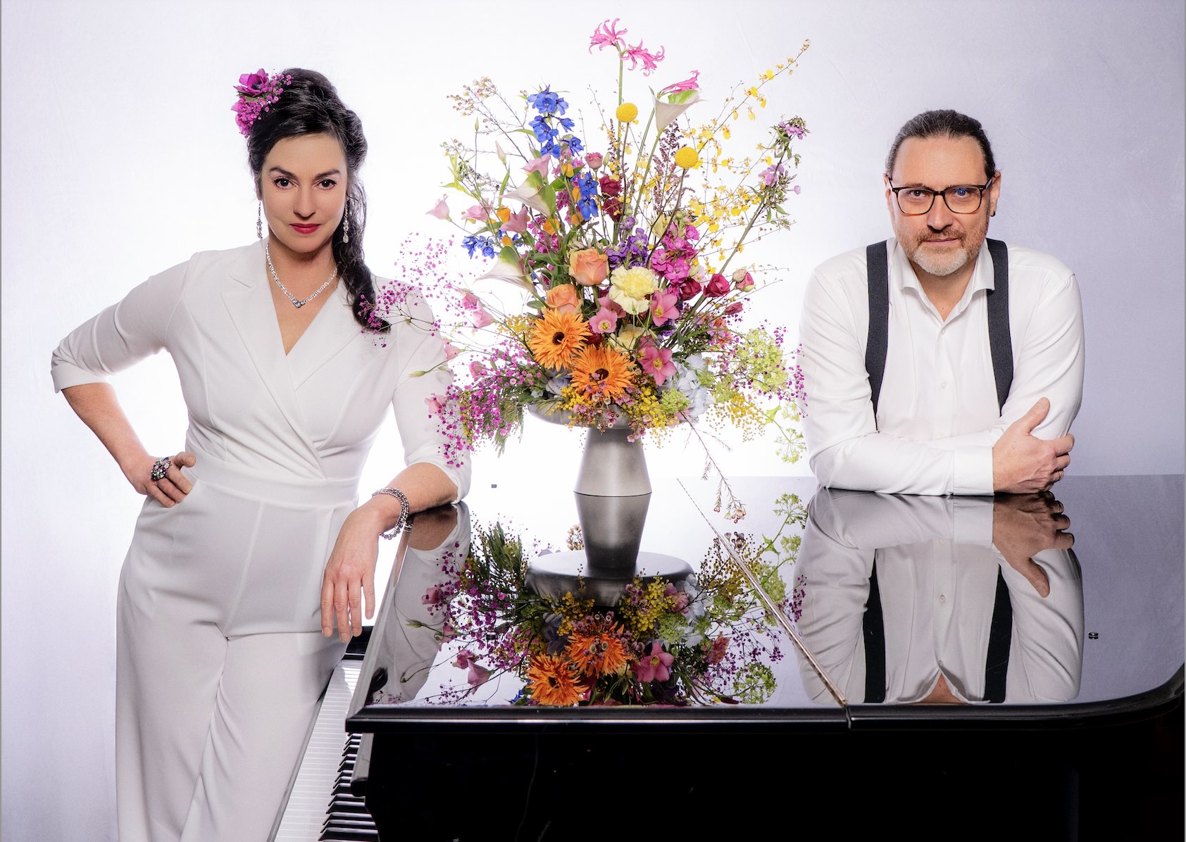 Franziska in weißem Anzug und Markus stehen am schwarzen Flügel, zwischen beiden ein prächtig bunter Blumenstrauß