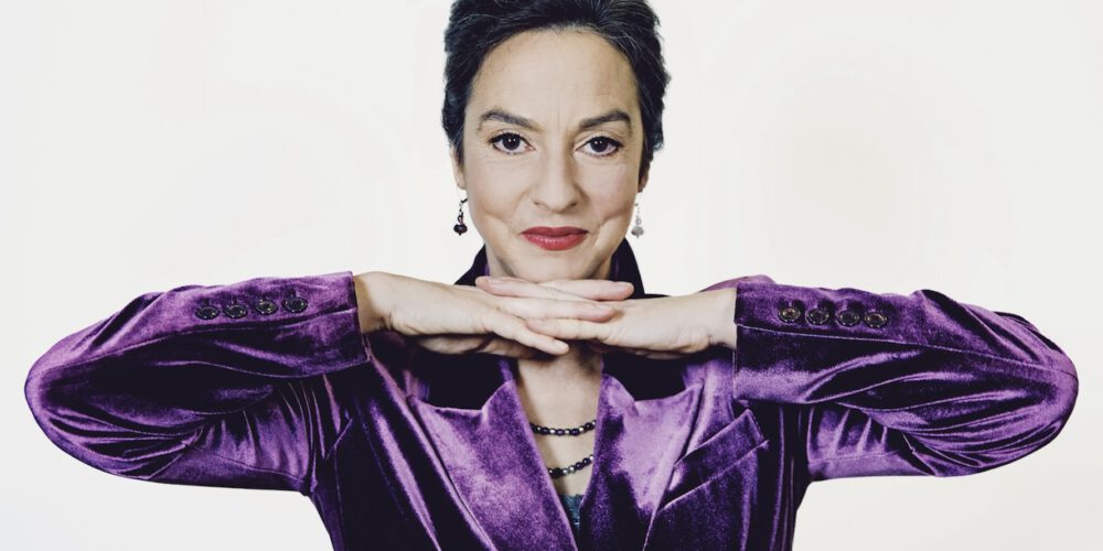 Franziska im lila Samt-Anzug vor weißem Hintergrund, Blick in die Kamera