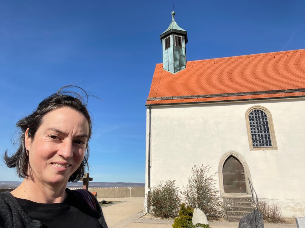 Frau steht vor kleiner BergKapelle